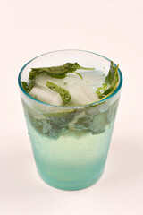 A glass with a refreshing mint and ice drink, set against a clear background