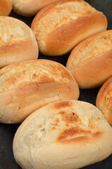 A close-up view captures a cluster of freshly baked, golden-brown bread rolls, showcasing their inviting texture