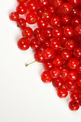 A close-up, top-down view shows a vibrant cluster of fresh red currants arranged diagonally on a clean white surface