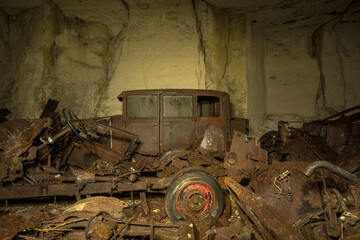 Rusty vintage car wrecks in an abandoned underground cave, showcasing decay and urban exploration...