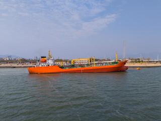 Fototapeta premium An Orange Cargo Ship at the Port with Clear Skies and Calm Waters