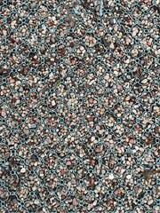 An overhead view of a modern ground reinforcement grid, with a teal-colored plastic mesh holding in place an assortment of small, colorful pebbles and gravel.