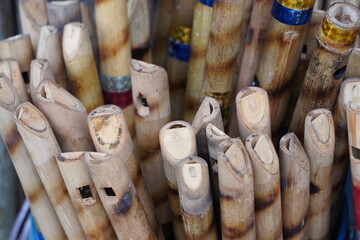 A collection of bamboo flutes are displayed for sale in a market