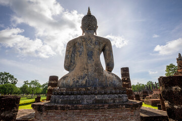 Fototapeta premium Backlit Buddha statue at the ruins of Wat Mahathat temple in Sukhothai Historical Park, Thailand.