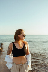 young beautiful girl with long hair and tattoo on vacation on the seashore. Traveling around sunny...