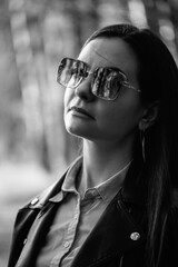 Portrait of a young beautiful long-haired girl in a black jacket outdoors. Black and white photo.