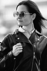 Portrait of a young beautiful long-haired girl in a black jacket outdoors. Black and white photo.