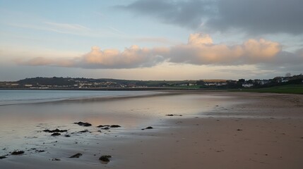 Fototapeta premium Serene coastal scene at sunset, showcasing a tranquil beach with calm waters reflecting the sky and distant coastline