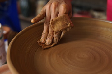 close up a hand making pottery using cloth as a tool