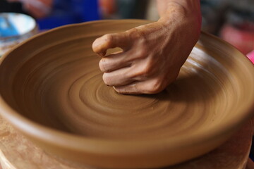 close up a hand making pottery using cloth as a tool