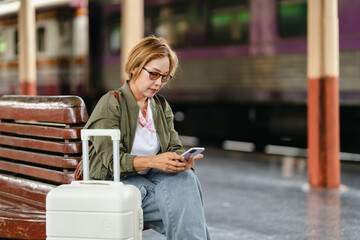 Mature female traveler using smartphone at train platform