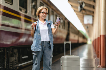 Woman traveler standing using smartphone at train station