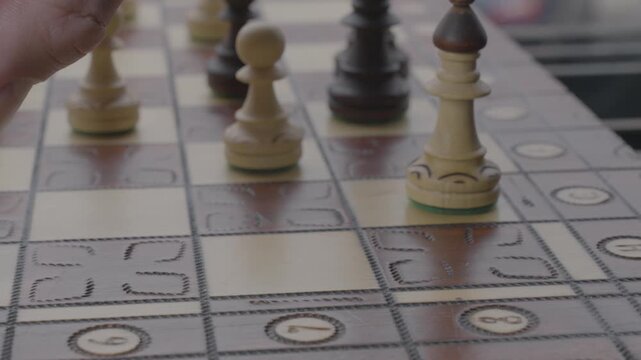 A man moves a chess piece on a chessboard