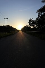 Golden hour illumination on a tranquil countryside road stretching toward the horizon capturing