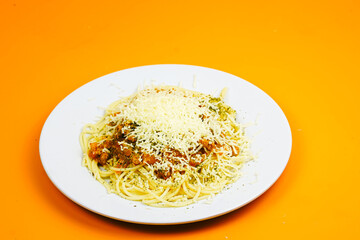 A generous serving of spaghetti bolognese topped with a mound of shredded cheese and herbs.