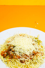 A generous serving of spaghetti bolognese topped with a mound of shredded cheese and herbs.