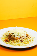 A generous serving of spaghetti bolognese topped with a mound of shredded cheese and herbs.