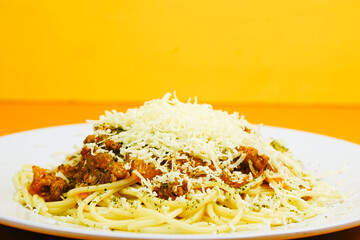 A generous serving of spaghetti bolognese topped with a mound of shredded cheese and herbs.