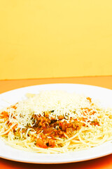 A generous serving of spaghetti bolognese topped with a mound of shredded cheese and herbs.