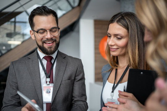Business people wearing id badges having meeting in office lobby