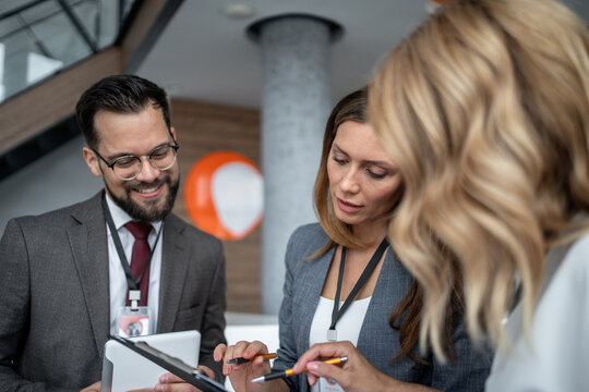 Businesspeople working together using digital tablet and documents in office lobby