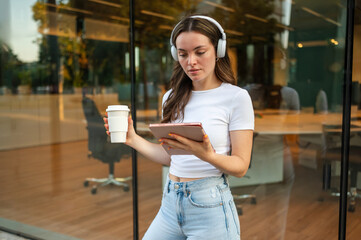 Businesswoman using digital tablet and drinking coffee outdoors