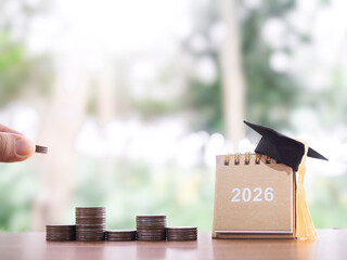 Study goals. 2026 desk calendar with graduation hat and stack of coins. The concept of saving money for education, student loan, scholarship, tuition fees in year 2026