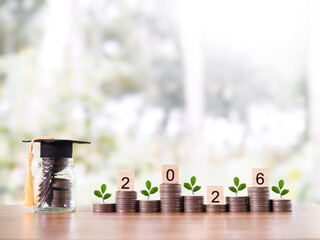 Glass bottle with graduation hat and stack of coins. The concept of saving money for education,...