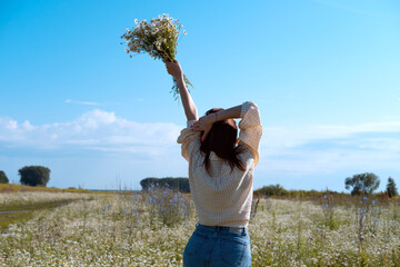 Young woman smiling while smelling daisies in field. Concept of peace and contentment. Summer bliss forever captured in this frame.