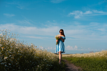 Young woman smiling while smelling daisies in field. Concept of peace and contentment. Summer bliss forever captured in this frame.