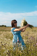 Young woman smiling while smelling daisies in field. Concept of peace and contentment. Summer bliss forever captured in this frame. vertical
