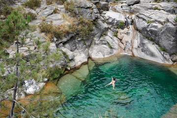 Girl taking a bath in the clear waters of Poco Azul natural pool in Penada Geres, Portugal
