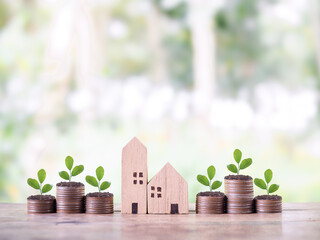 Miniature house and plants growing up on stack of coins. The concept of saving money for house, Property investment, House mortgage, Real estate.