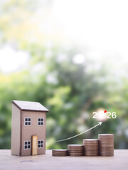 Miniature house and stack of coins with arrow rising up. The concept about price of house is growing up, Property investment, House mortgage, Real estate in year 2026