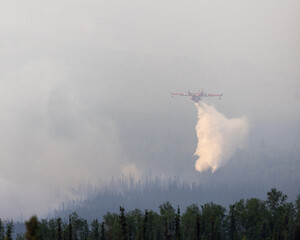 Airplane dropping water on wildfire.