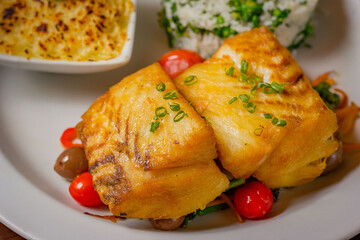 Close-up of a gourmet dish with grilled fish fillet, vegetables, rice and gratin side. Fine dining and gastronomy concept.