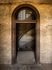 Rustic Arched Doorway Framing a Curved Iron Staircase in an Abandoned Historic Chateau