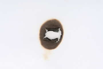 Burnt hole isolated on white paper. burns borders paper close up. Paper burn black stain mark close up.