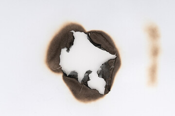 Burnt hole isolated on white paper. burns borders paper close up. Paper burn black stain mark close...