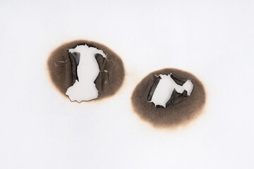 Burnt hole isolated on white paper. burns borders paper close up. Paper burn black stain mark close up.