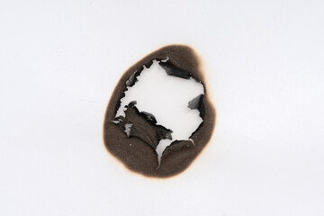 Burnt hole isolated on white paper. burns borders paper close up. Paper burn black stain mark close...