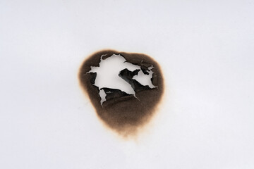 Burnt hole isolated on white paper. burns borders paper close up. Paper burn black stain mark close up.