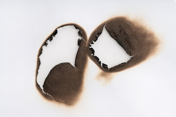 Burnt hole isolated on white paper. burns borders paper close up. Paper burn black stain mark close up.