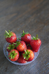 top view several fresh strawberries Placed in a clear plastic glass lid on a wooden table background, fruit, health, food, copy space