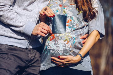 Young pregnant couple marking child birth day in calendar. Baby expecting concept. Planning of future. Adult man and pregnant woman demonstrating calendar and pointing at calendar baby birth date