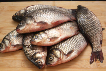 Fresh crucian carps lie on a cutting wooden board. Concept - cooking.
