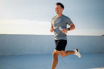 Joyful runner enjoys a sunny workout on a rooftop in the early morning
