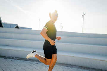 Runner enjoys a sunny day as he sprints along modern outdoor steps