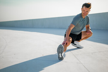 Stretching under the sun at a rooftop gym during a bright afternoon workout