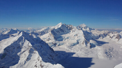 Aerial View of Snowy Mountain Ridges Casting Long Shadows in Late Afternoon Sunlight